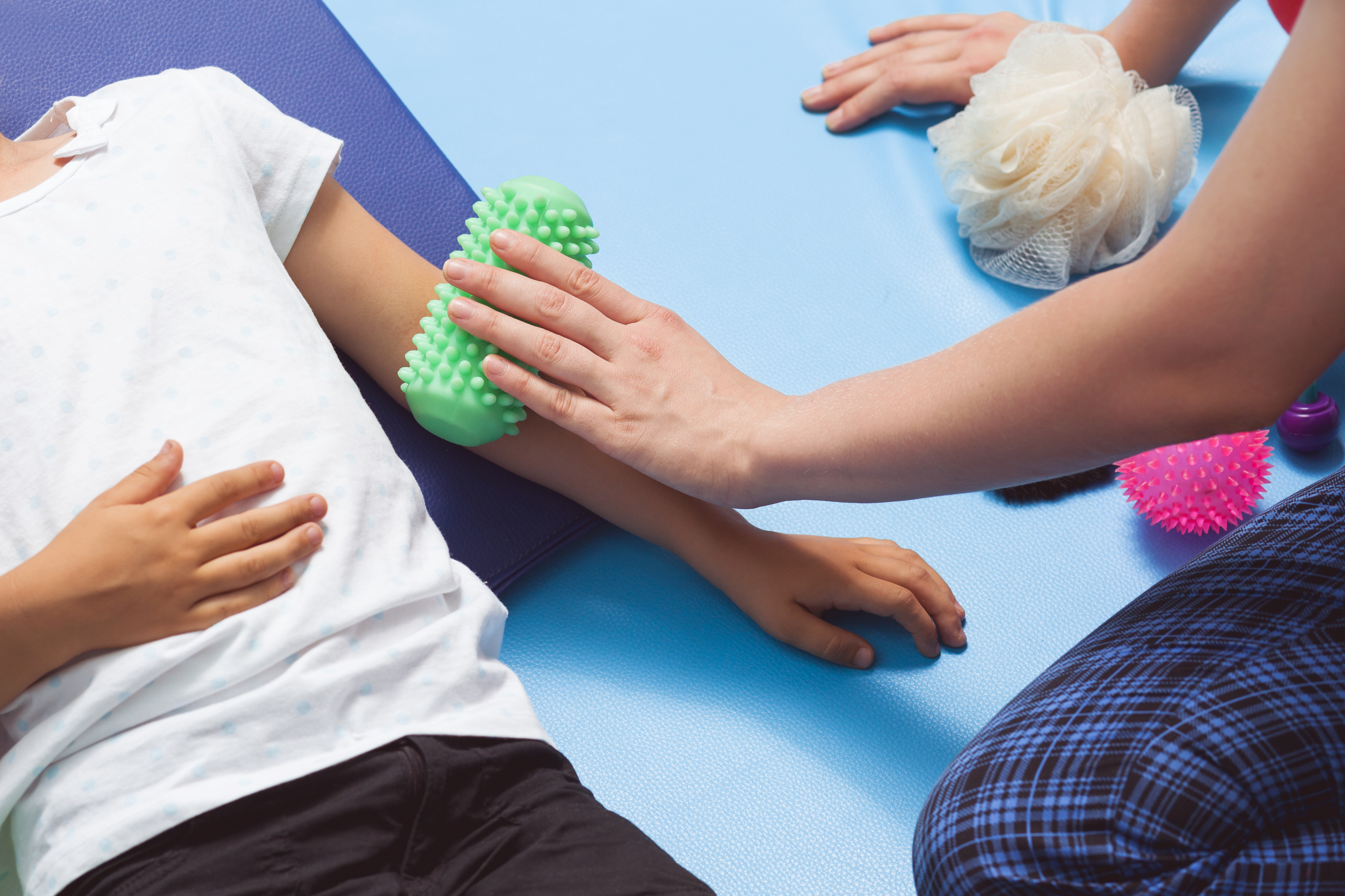 Massage roll in sensory therapy Therapist making a roll massage on young girl's arm